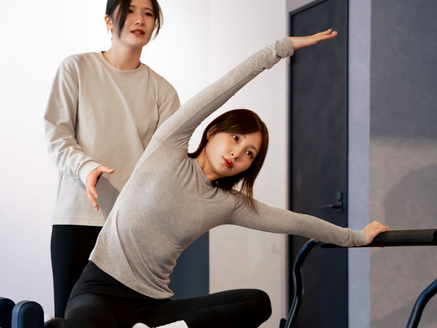 トレーナーの補助で身体の側面を伸ばしている様子